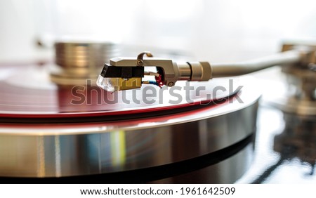 tonearm cartridge close up against red vinyl background