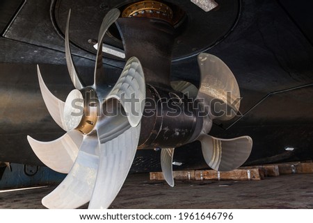 The bottom of a ship supported in dry dock with azimuth propulsion and twin propellers aft. Royalty-Free Stock Photo #1961646796