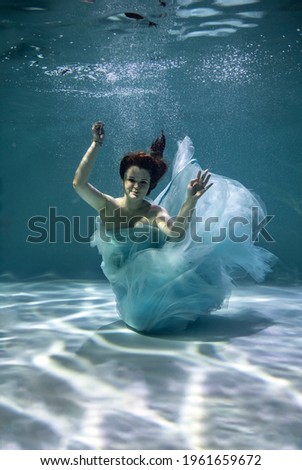 beautiful girl in blue and white tiles underwater on a blue background