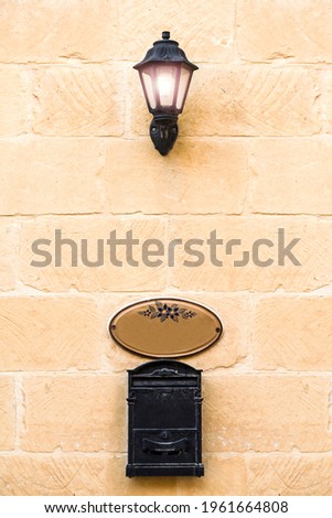 Lighting Lantern on the stone wall with the nameplate and key box bellow