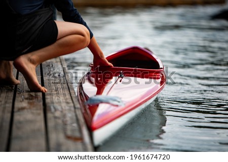 Athlete, canoeist, holding a sports canoe in his hands at the pier by the lake  Royalty-Free Stock Photo #1961674720