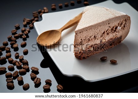 Delicate mousse cake with ground coffee beans and hazelnuts on a dark stone background
