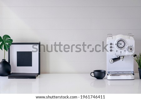 Mockup white coffee machine, cup, wooden frame and houseplant on white table with  copy space.