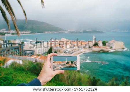 Smartphone with a photo of ancient town on the background of Budva