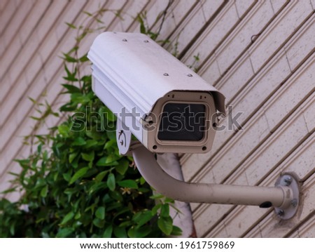 Security camera on a wall with plants in the background