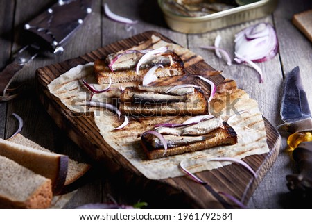 sprat sandwich on a wooden board with a knife