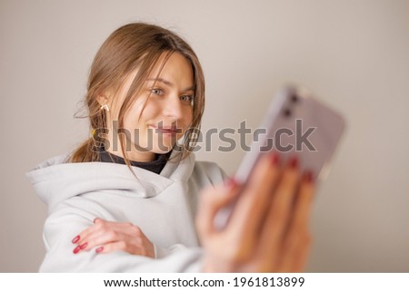 Young beautiful brunette girl close-up on a white background, taking a selfie on her phone. Smiling and posing.