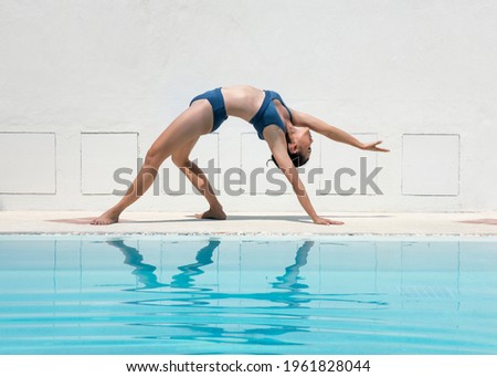 Beautiful young fit young woman doing a wheel pose by the pool  Woman practicing yoga or pilates on the pier. Bridge Pose, Urdhva Dhanurasana (Upward Bow), Chakrasana (Wheel). Vacations Concept