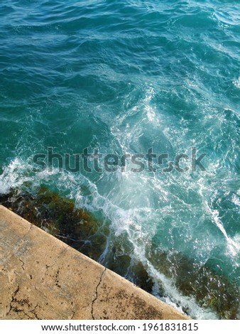 Top down view of a wave breaking on a stone pier