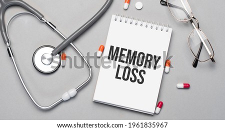 In the notebook is the text memory loss, next to a stethoscope, pills and glasses.