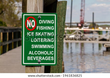 An extensive list of actions forbidden on the dock area are shown. The sign says no to diving, swimming, ice skating, loitering, fishing and alcoholic drinks. Supressive authoritarian regime concept.