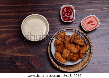 Fried chicken pops with ketchup, chili sauce and mayo on wooden background.