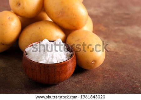 Potato starch powder in a bowl with raw potatoes Royalty-Free Stock Photo #1961843020