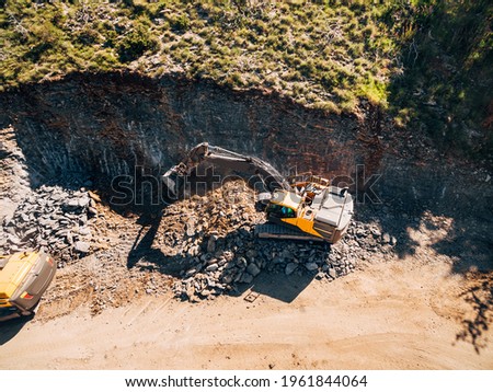 Yellow tracked tractor is working on the extraction of rock. View from above