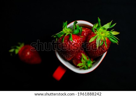 Delicious,juicy strawberries in and red and white cup on a black background. 