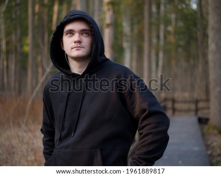 A guy in a black tracksuit, a portrait on a forest background, the sun at sunset, the guy goes in for sports, the concept of a healthy lifestyle.