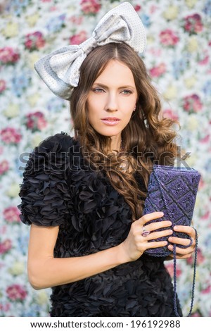 Beautiful brunette young woman wearing dress and holding handbag