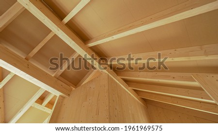 Beautiful view of the massive ceiling beams of a modern cross laminated timber house. Gorgeous hardwood structure of the ceiling of a contemporary glue laminated housing project under construction. Royalty-Free Stock Photo #1961969575