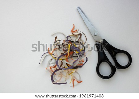 Old scissors and pieces of cut colored paper on a white background.