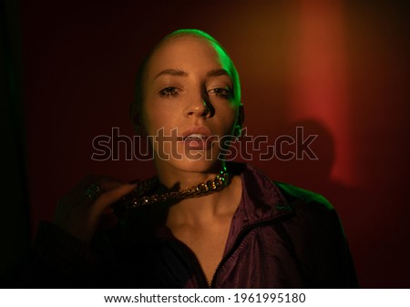 Woman standing at the dim light and posing to the camera while holding her chain