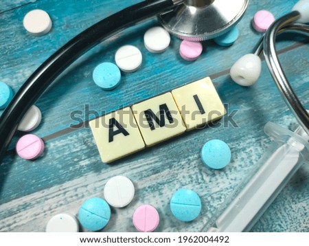 Text AMI (Acute myocardial infarction) on a table with a stethoscope,syringe and pills. Medical concept.