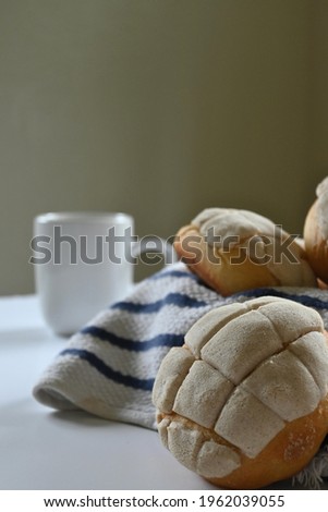 closeup of homemade Mexican vanilla shells with white and blue cotton dishcloth and white minimalist mug with handle on dark background and white surface