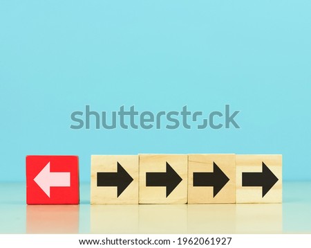 individual and standing out from the crowd concept. Red wooden cubes with white arrow facing the opposite direction black arrows.