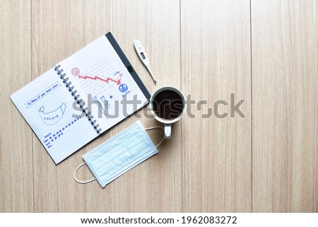 The memo of covid 19 passed years diary on wooden floor with mask coffee cup and thermometer , diary of covid-19 show graphic sketch of mask, vaccine and hope, global economy,with copy space for text