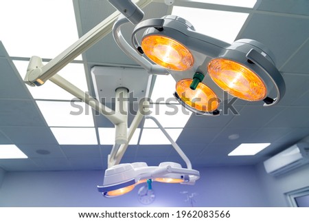 Two surgical lamps in operation room. Blue cast light represent purity and clinical mood. File for hospital brochure or medical article.