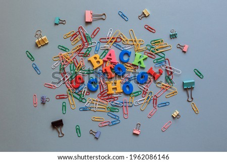 Back to school. The words are laid out in letters from a plastic magnetic alphabet among colored paper clips.