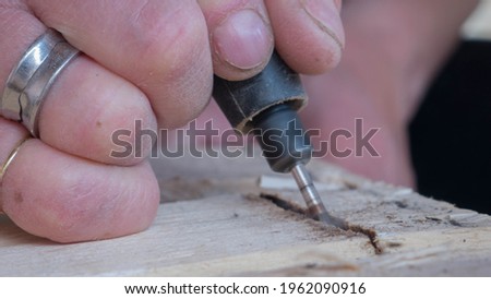 close-up of worker's hand with tools hacking wood with smoke that is seen from overheating of the tool