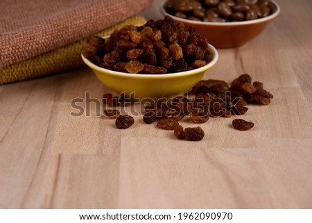 Dried raisins in a bowl on a wooden background stock images. Raisins sultanas still life photo images. Raisins on the table stock images. Raisins on a wooden background with copy space for text