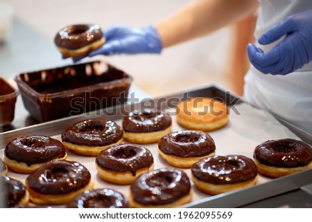 Chocolate topping on donuts in a working atmosphere in a candy workshop. Pastry, dessert, sweet, making Royalty-Free Stock Photo #1962095569