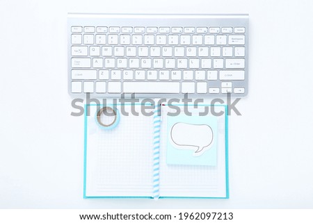 Computer keyboard with notepad, pen and speech bubble on white background