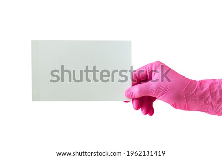 Female hand in pink protective rubber glove holding blank photo card on pink background.