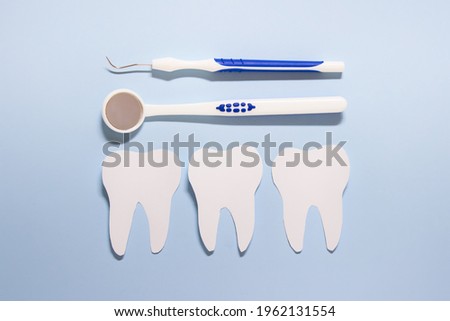 Oral health dentistry composition with dental accessory and three white paper tooth on blue background.