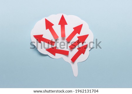 Paper composition with large brain outline and many red arrows on blue background.