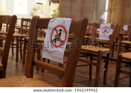 Social distancing in church as new normal in corona and covid-19 times. The seats must be left empty in order to keep the distance. Do not sit icons are attached on the chairs that cannot be occupied.