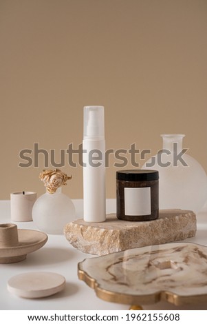 Aesthetic minimalist beauty care therapy concept. Spray bottle, cream, marble stone with flower against neutral beige background. Organic body skin treatment product composition