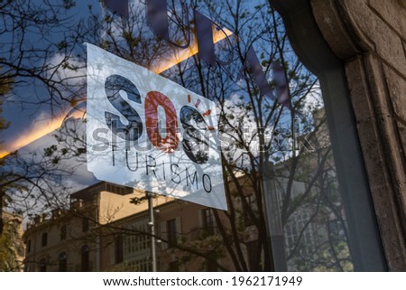 SOS tourism poster in a glass window reflecting the city of Palma de Mallorca. Economic crisis caused by the Coronavirus pandemic Royalty-Free Stock Photo #1962171949