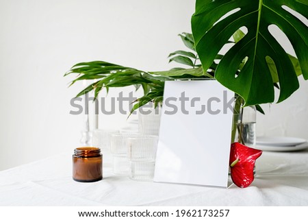 Mock up label the blank menu frame in bar restaurant, Stand for booklets with white paper, wooden tent card on restaurant table with tropical bouquet