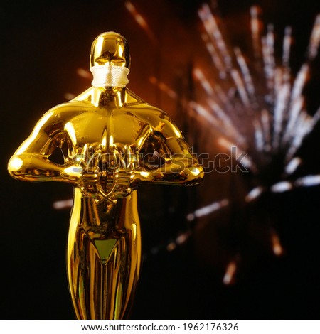 Hollywood Golden Oscar Academy award statue in medical mask on fireworks background. Success and victory concept. Oscar ceremony in coronavirus time