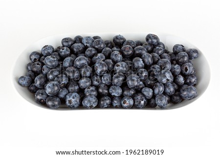 full plate of blueberries a white background