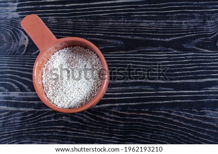 Sesame seeds in a brown dish on a dark background of kopi space