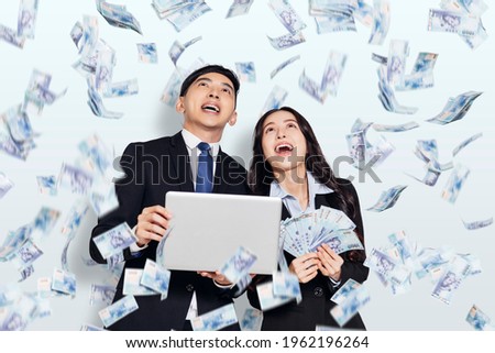 Excited young business man and woman watching the money rain