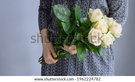 Young woman holding a bouquet of flowers. A bouquet of white roses in her hands. White roses. Girl in a dress.
