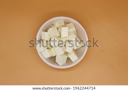 Homemade Indian paneer cheese made from fresh milk and lemon juice, diced in a wooden bowl on a gray stone background. Paneer Cubes Close up Royalty-Free Stock Photo #1962244714