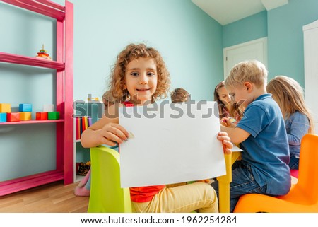 Happy little girl showing her drawing to the camera