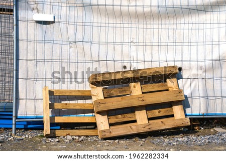 Wooden pallets leaning against a metal mesh. Construction site.