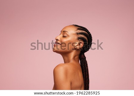 Side view of a female model having healthy and flawless skin. African american woman with braided hairstyle on pink background. Royalty-Free Stock Photo #1962285925
